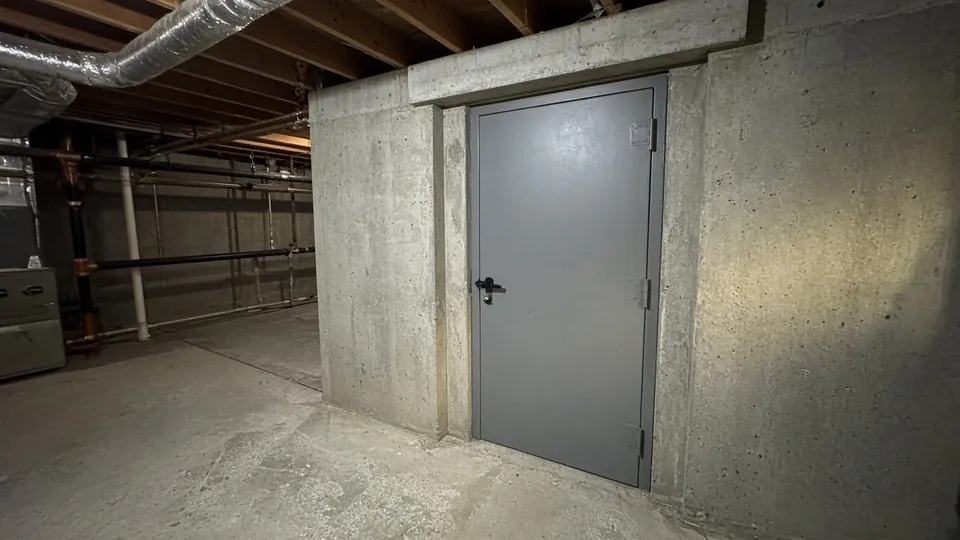Reinforced concrete shelter room with a steel door in a home basement