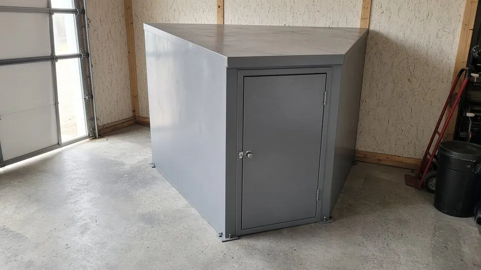 Above-ground steel storm shelter anchored to a garage floor